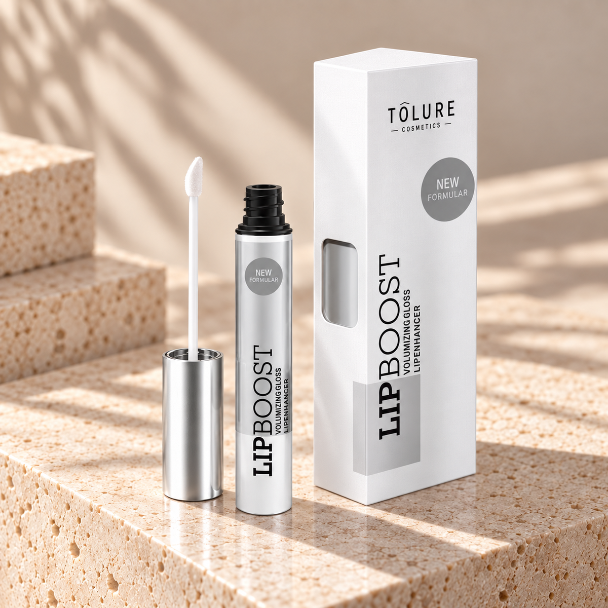 Tolure LipBoost Clear lipgloss på travertin i samme beige billedstil.